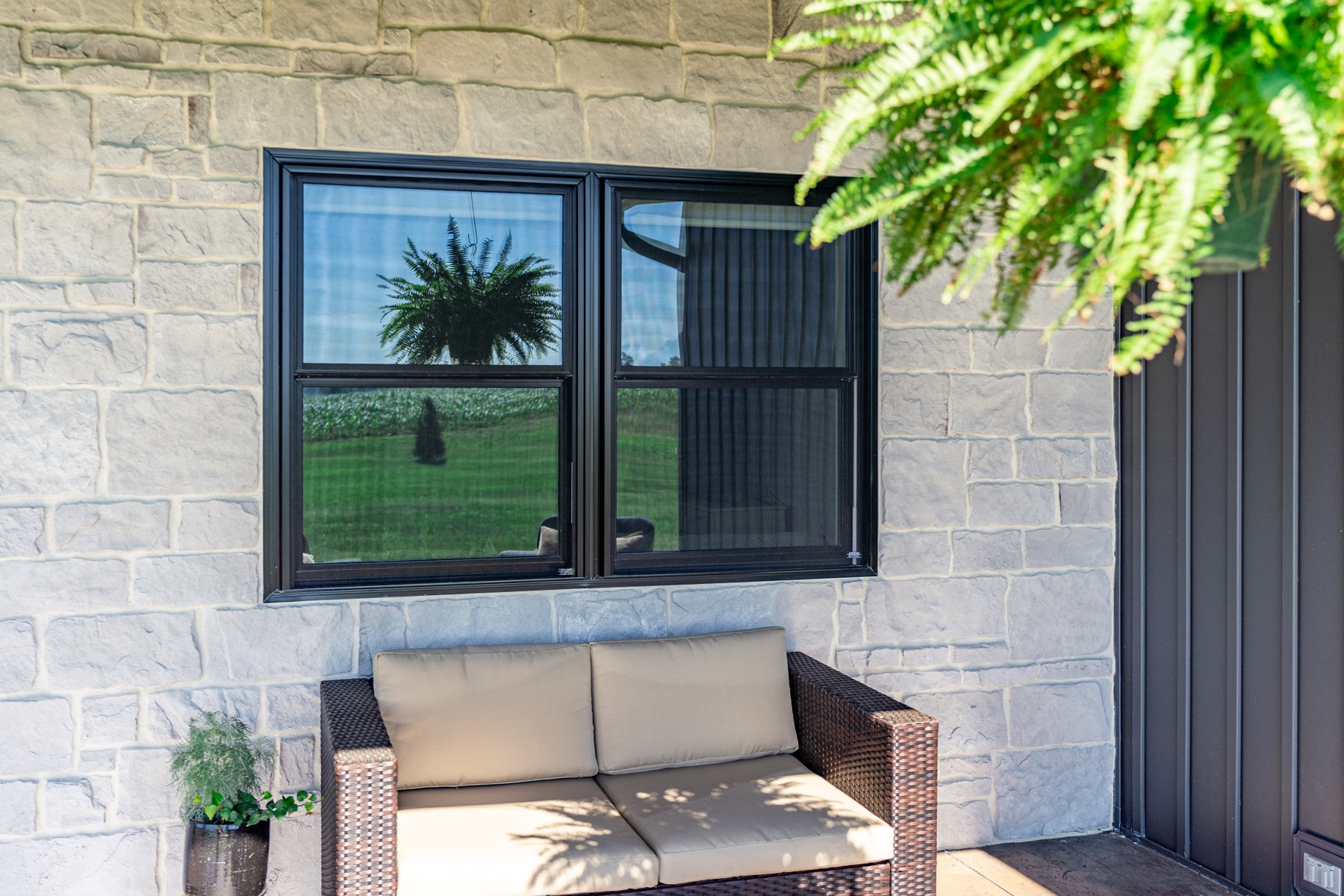 Black double hung windows on a stone patio wall